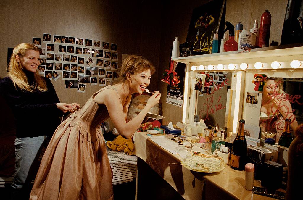 woman in a dressing room eating and looking at a mirror