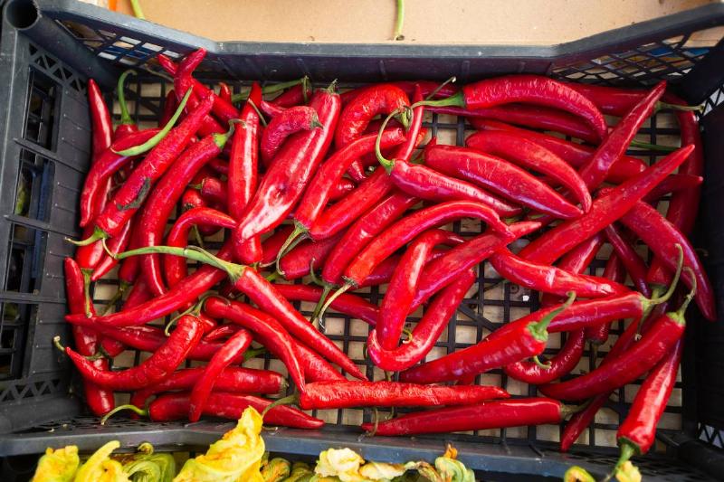 A pile of red chili peppers sit against a white background.