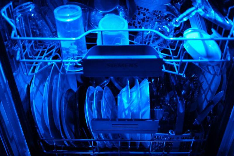 13 April 2020, North Rhine-Westphalia, Cologne: Washed dishes are in an open dishwasher with blue lighting. Photo: Oliver Berg/dpa