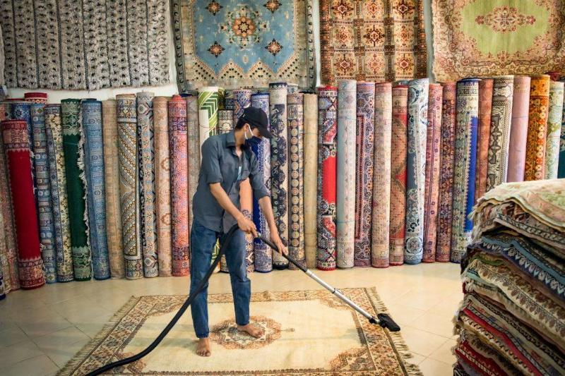 A Moroccan rug dealer cleans a carpet at a shop in the city of Sale, north of the capital Rabat, on June 3, 2020, during the novel coronavirus pandemic. - Artisans in Morocco have been starved of income for almost three months because of the COVID-19 pandemic. The crafts industry represents some seven percent of GDP, with an export turnover last year of nearly 1 billion dirhams ($100 million).