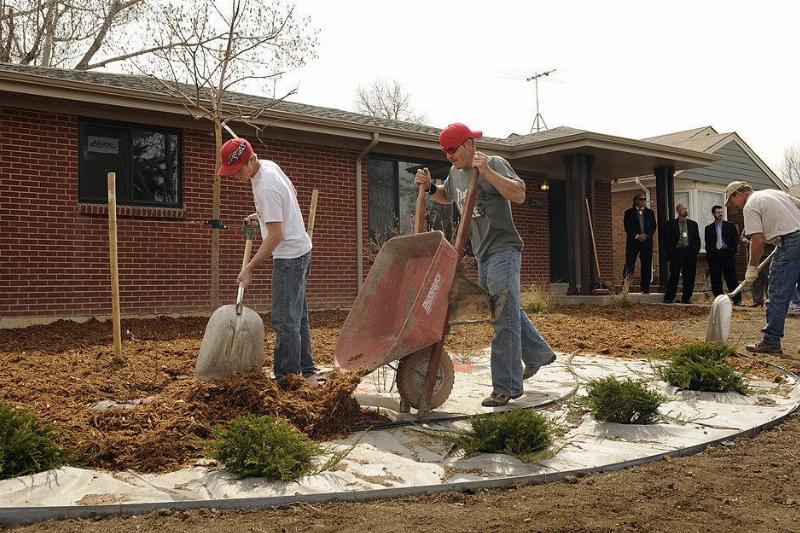 A landscaping crew from Prairie Snow Enterprises out of Keenesburg, CO, place mulch around new plants in front of a new HUD rehab home in Aurora