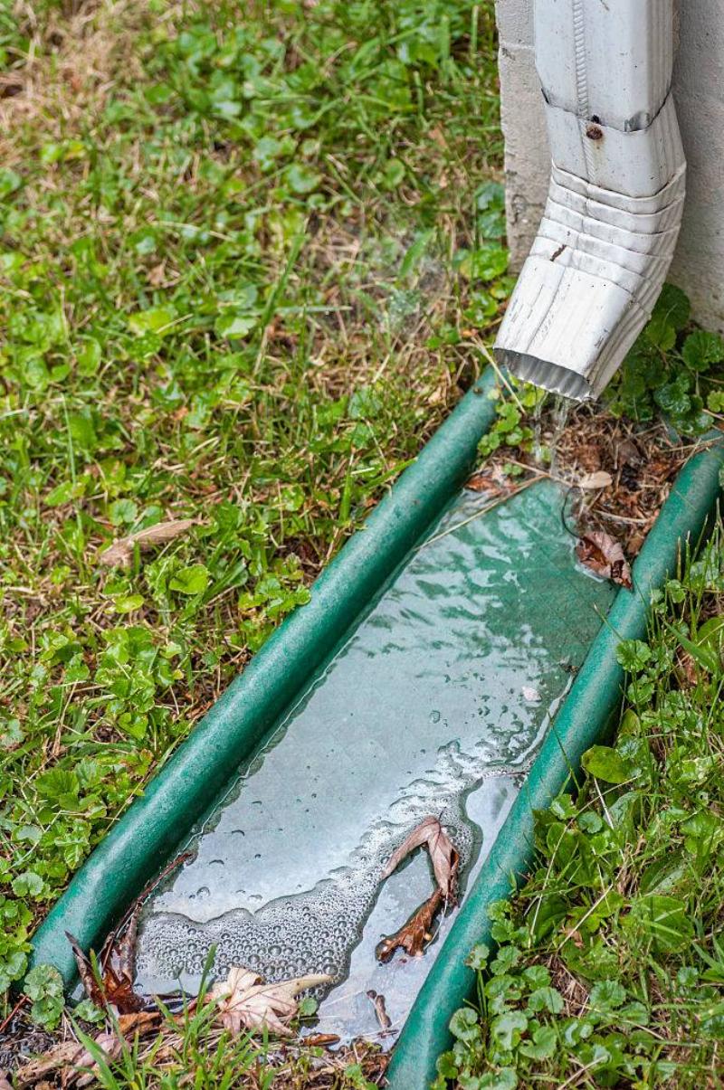 A pipe for carrying rainwater from a rain gutters called a downspout, waterspout, downpipe, drain spout, roof drain pipe, leader, or rone. At the end is a downspout silencer and a green splash block below..