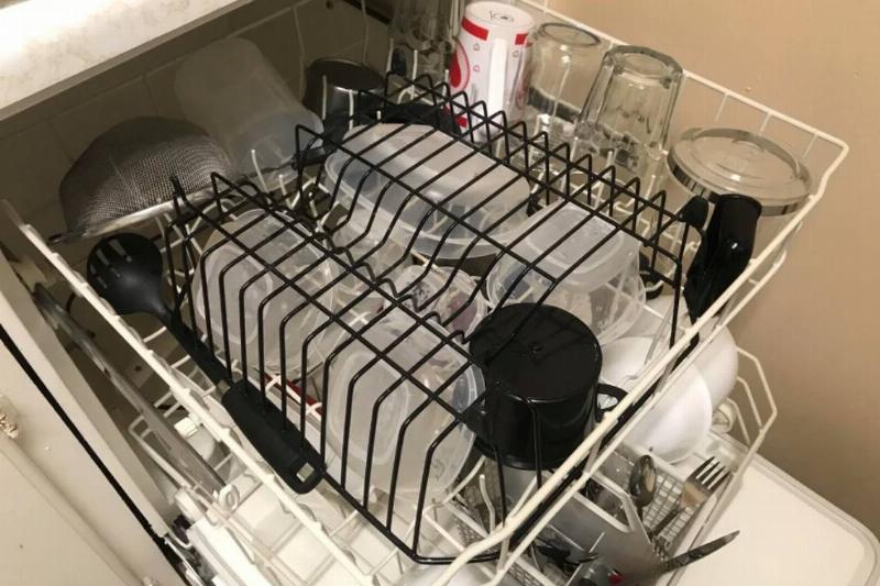 standing dish rack flipped over on top of tupperware containers in dishwasher top rack