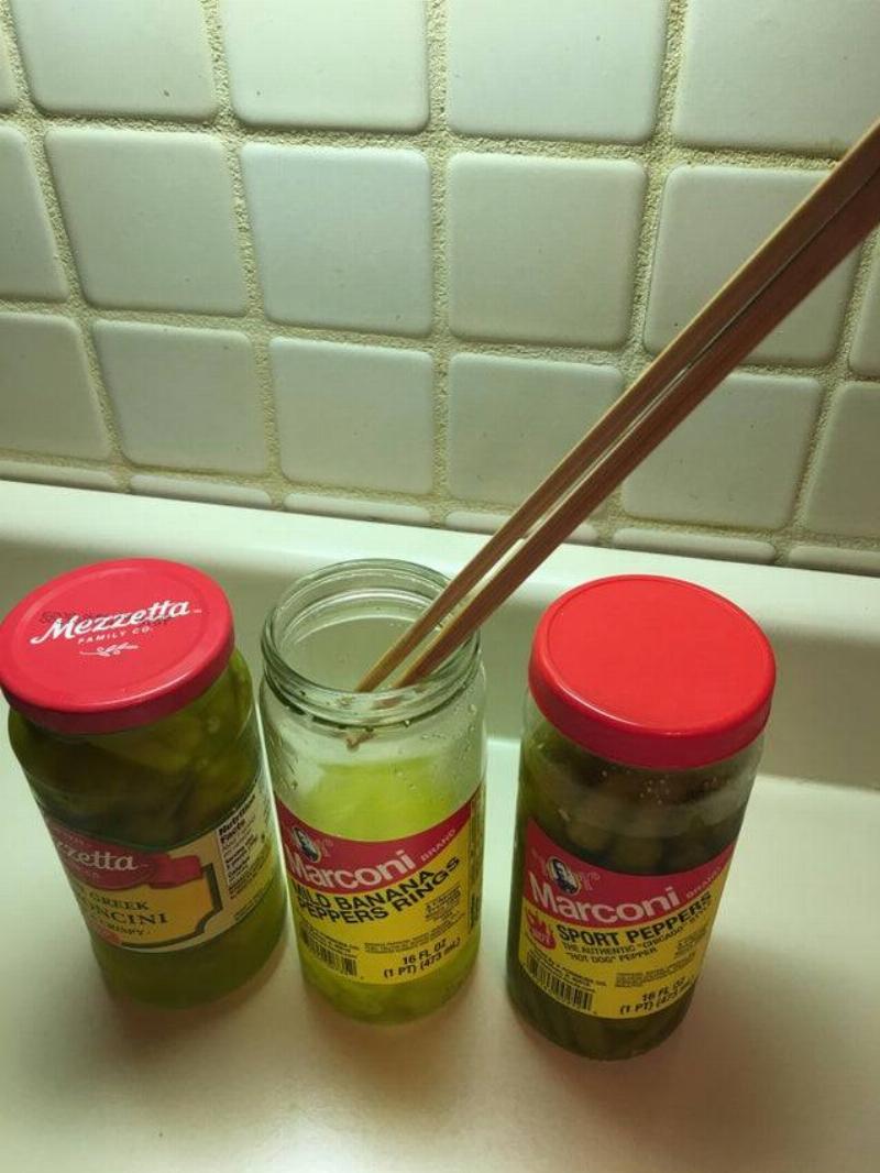 chopsticks being used to get stuff out of a tall container 