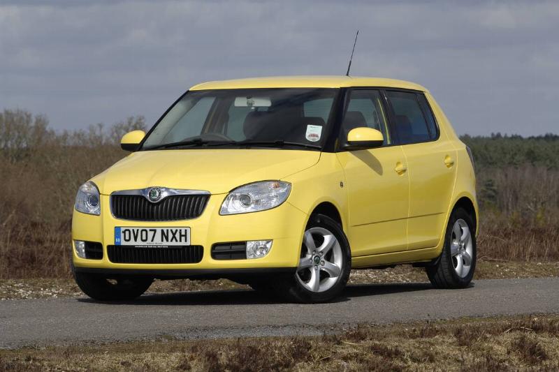 A yellow Škoda Fabia 2 drives down a road.