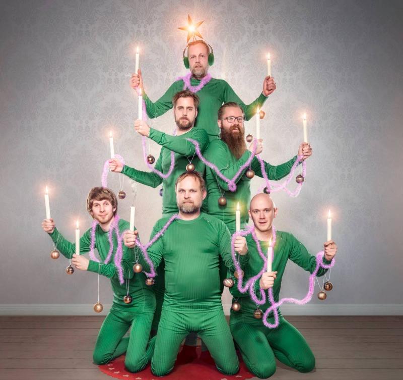 group of men in green holding candles to look like a shape of a christmas tree