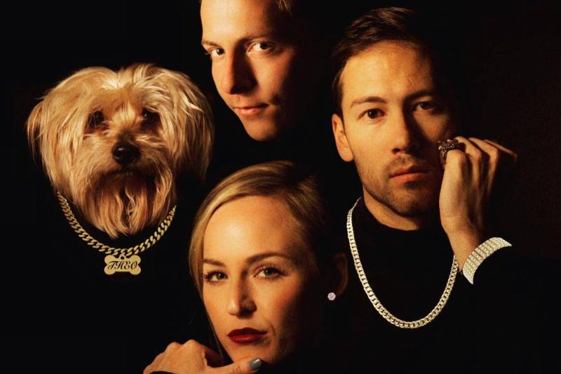 three people in black wearing chains and dog wearing a chain