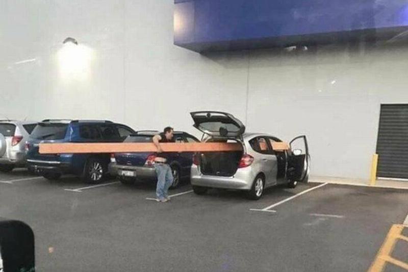 trying to fit a huge plank of wood into small car