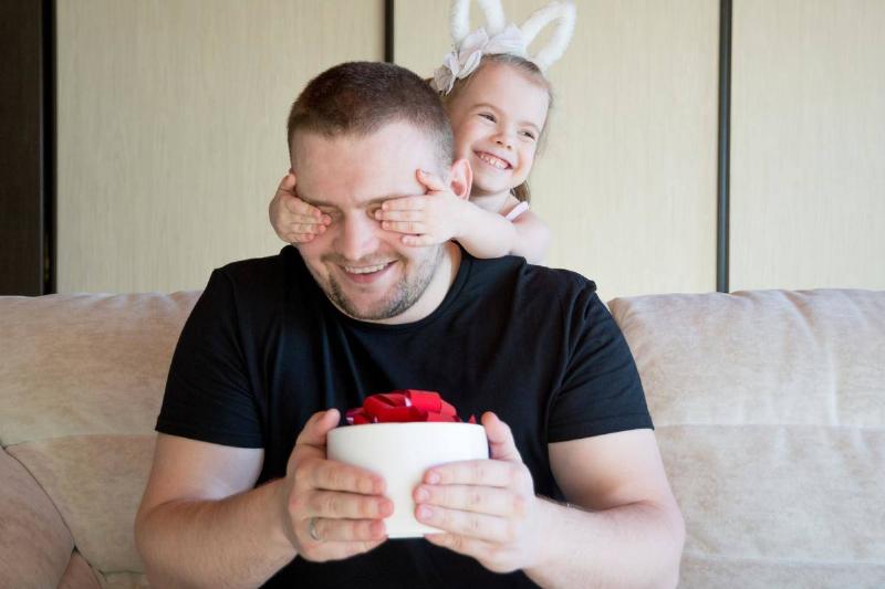 young girl covering dad's eyes