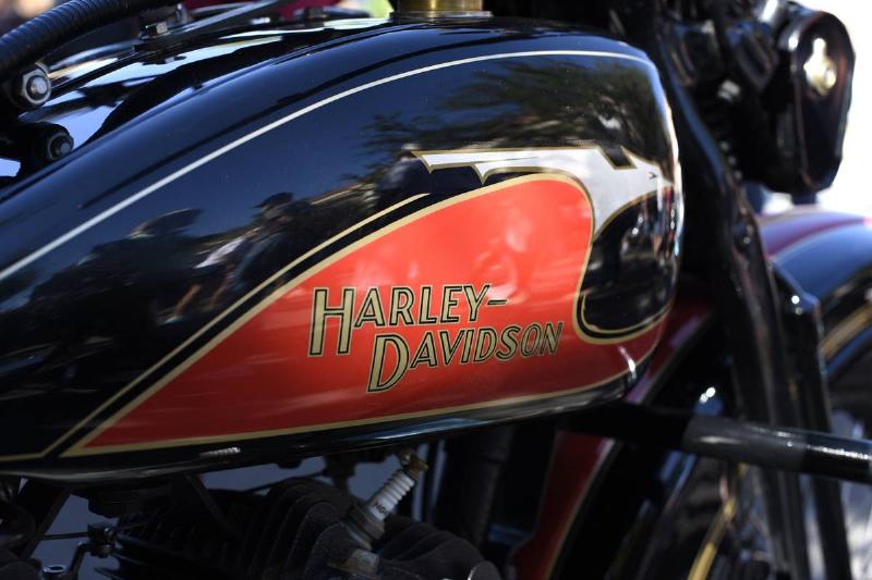 A close-up of a motorcycle shows a Harley Davidson logo.