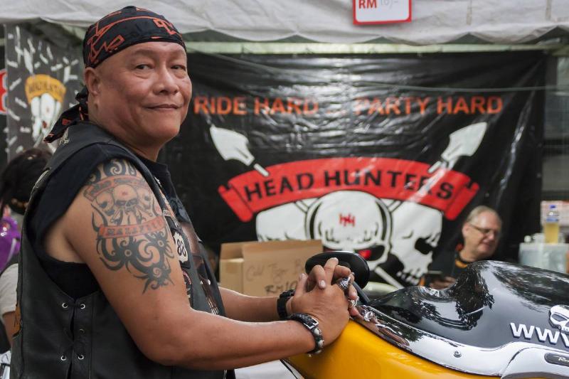 A biker from the motorcycle club Head Hunters is seen in front of a flag.