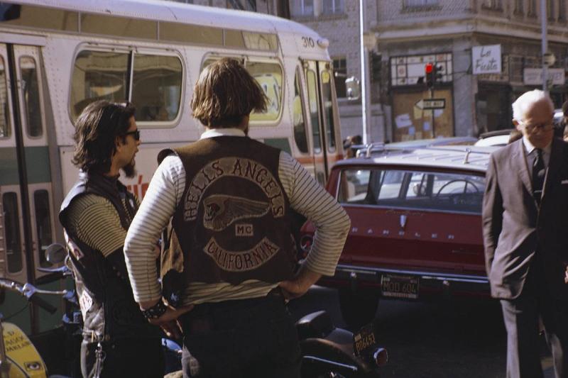 An elderly man walks by two members of the Hells Angels.