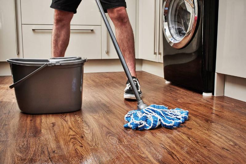 man cleaning wooden floor with mop and bucket