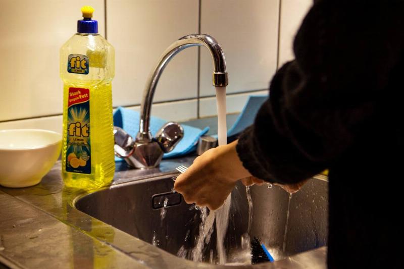one person washing dishes by hand in sink in berlin