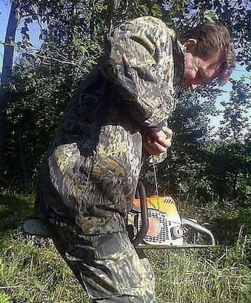 person in camo with chainsaw between legs