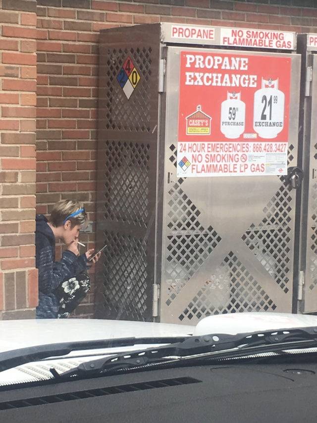 girl smoking in front of propane containers
