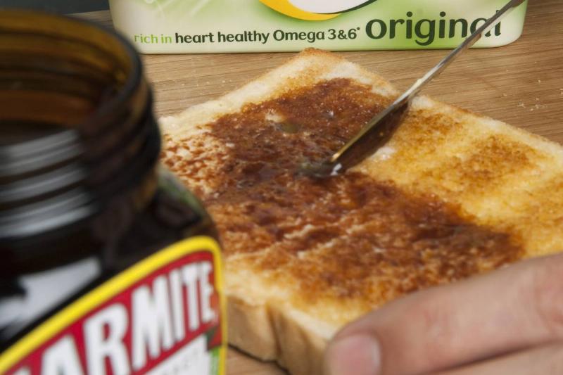 A person spreads marmite on white toast.