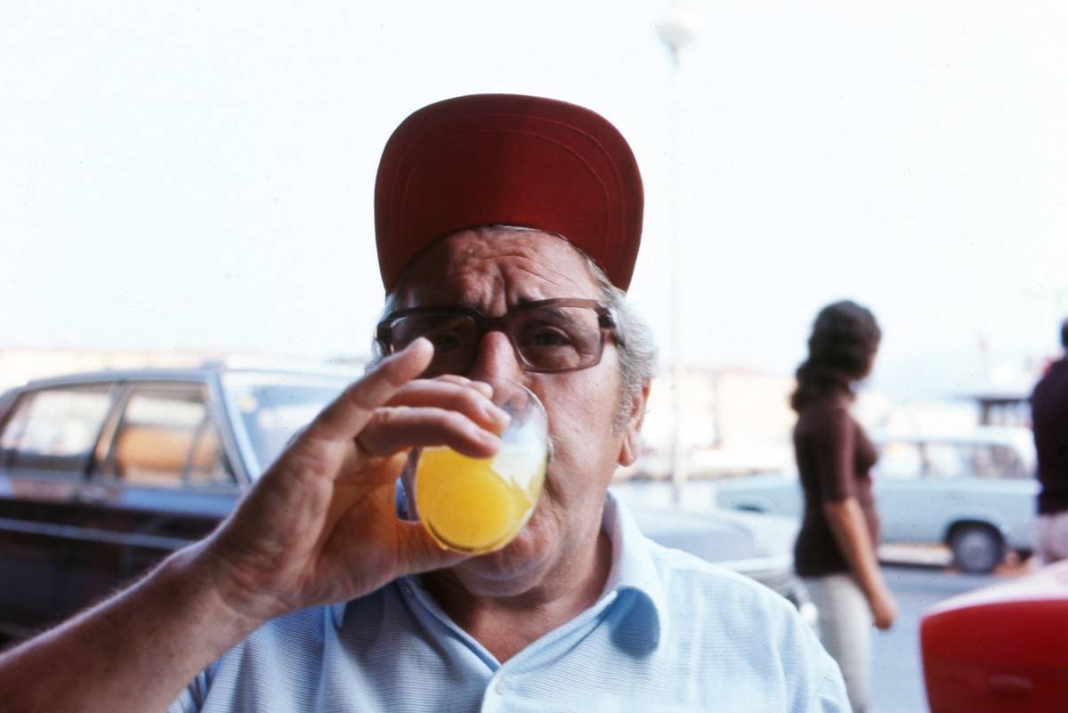 A man drinks a glass of orange juice.