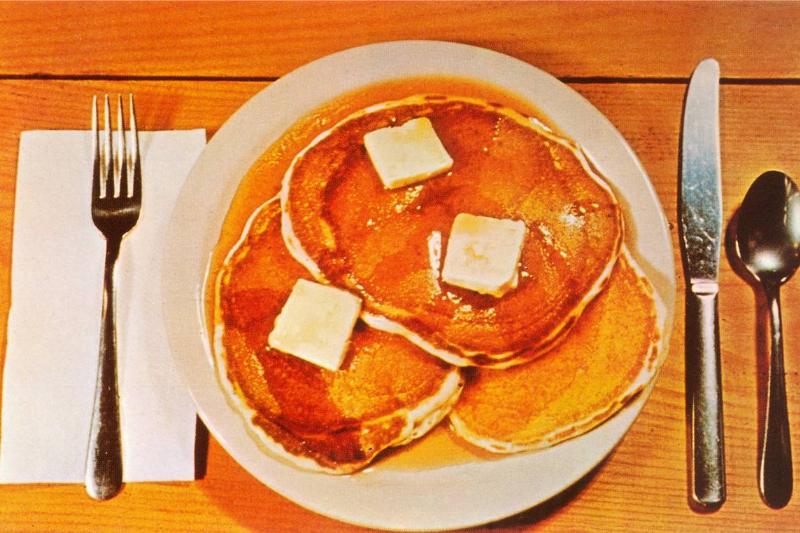 A vintage color photograph shows pancakes on a place setting.