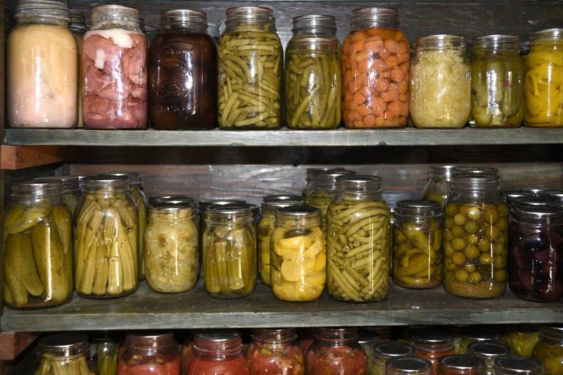 A variety of preserved vegetables are seen in jars.
