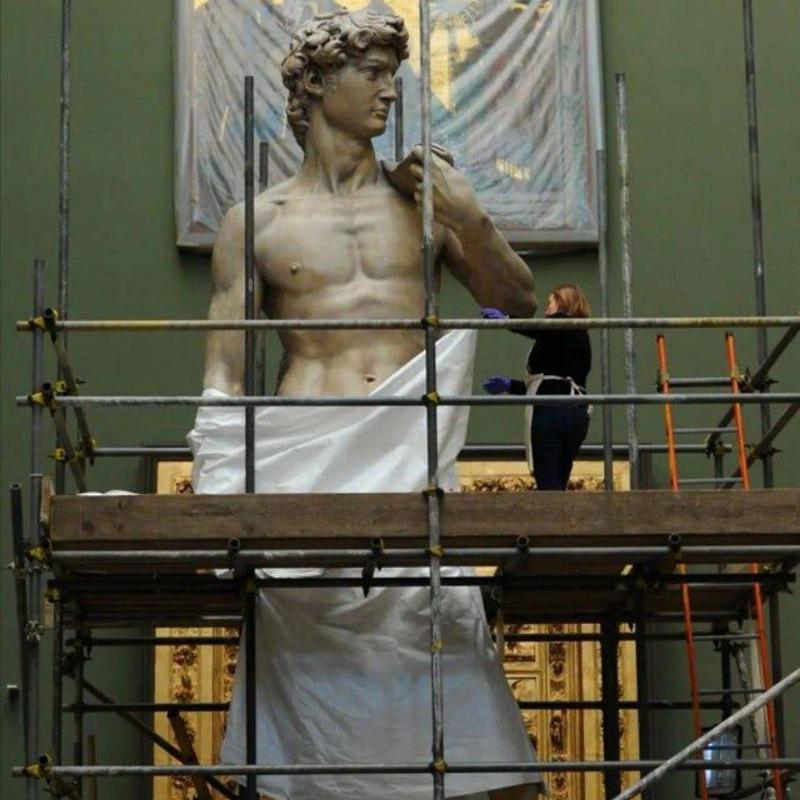 a picture of someone standing next to Michelangelo's David