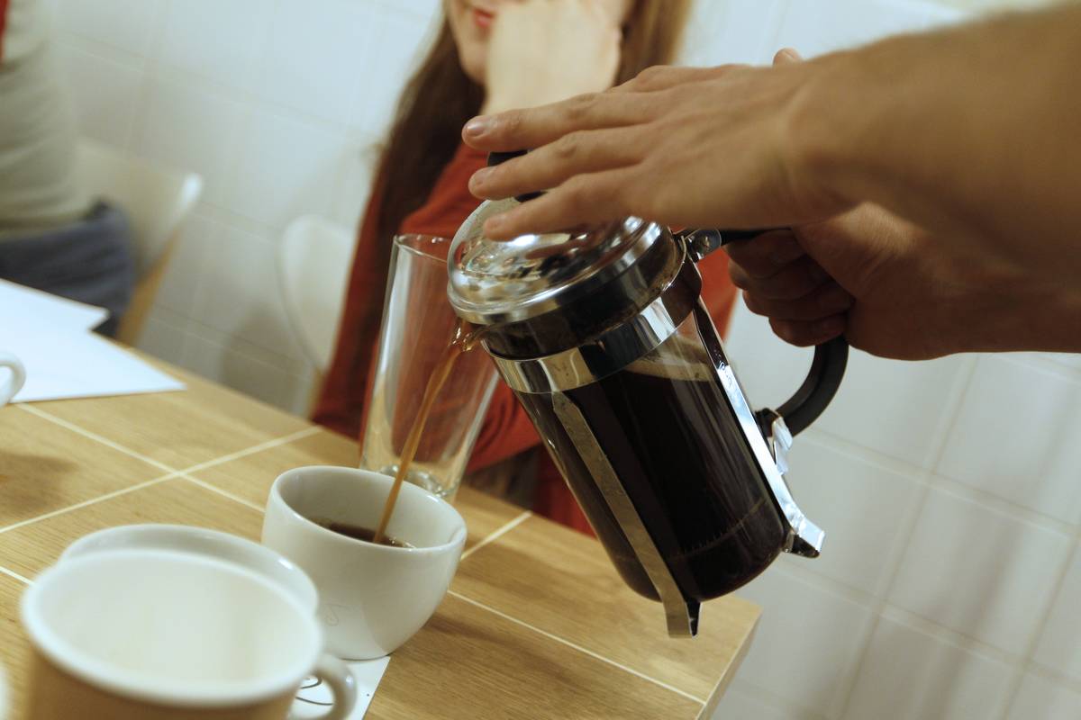 A waiter pours hot coffee into a mug at a restaurant.