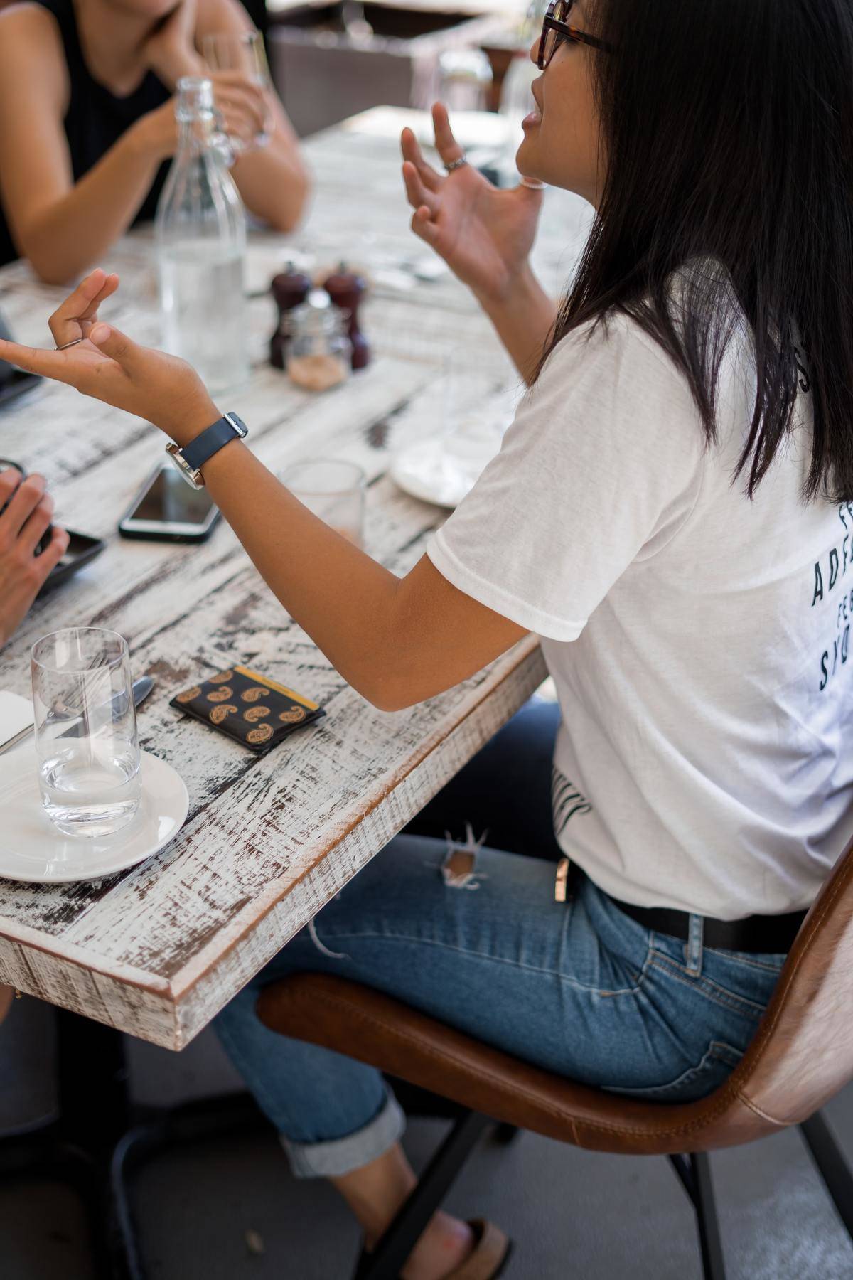 A woman speaks with hand gestures at a table.