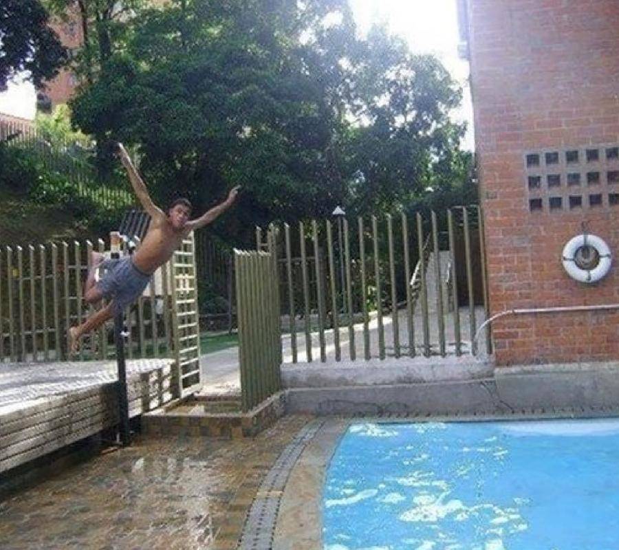 boy trying to jump into pool, about to hit the deck