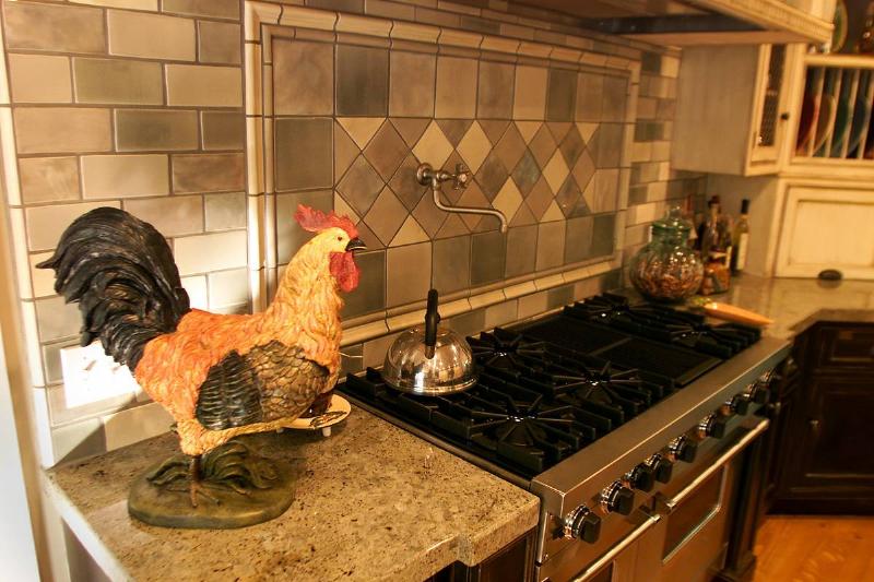 A kitchen has been remodeled in the farmhouse style with a rooster sculpture on the counter.