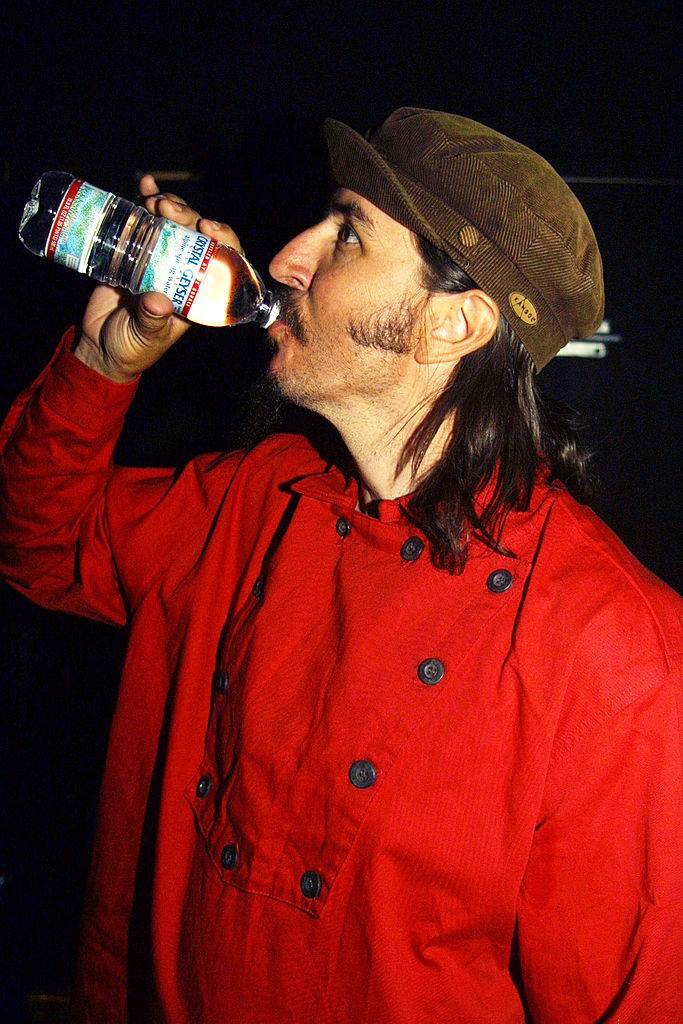 Les Claypool drinking a bottle of crystal geyser water