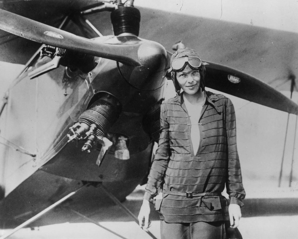 A female pilot stands in front of her plane, 1937.