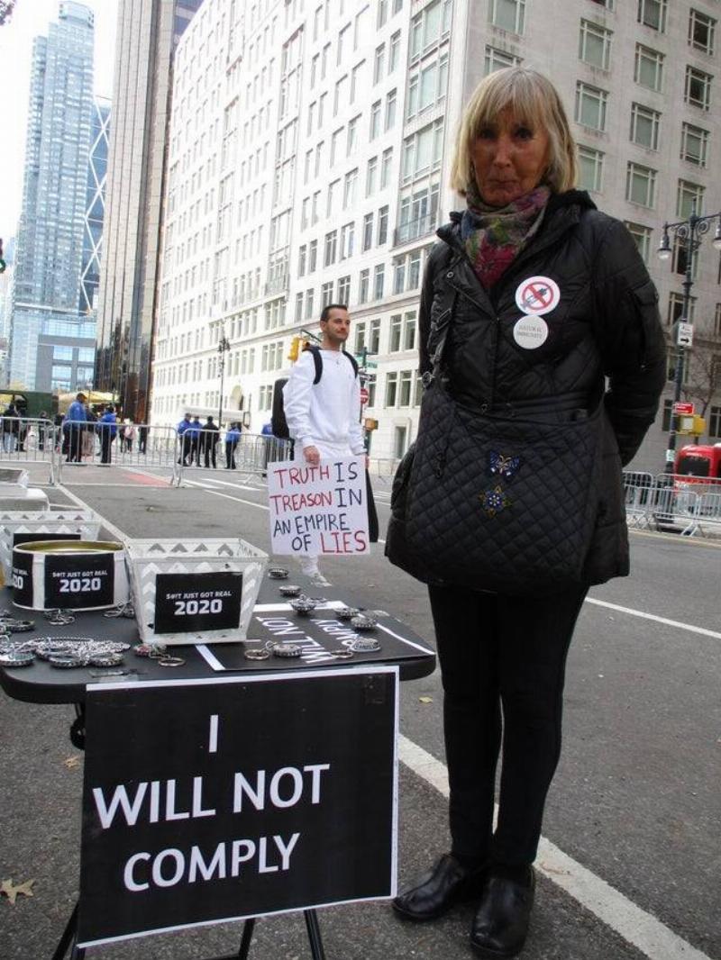 Woman standing beside table with sign saying they will not comply. 
