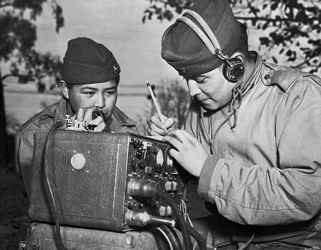 A two-man team of Navajo code talkers relay orders over the field radio using their native language