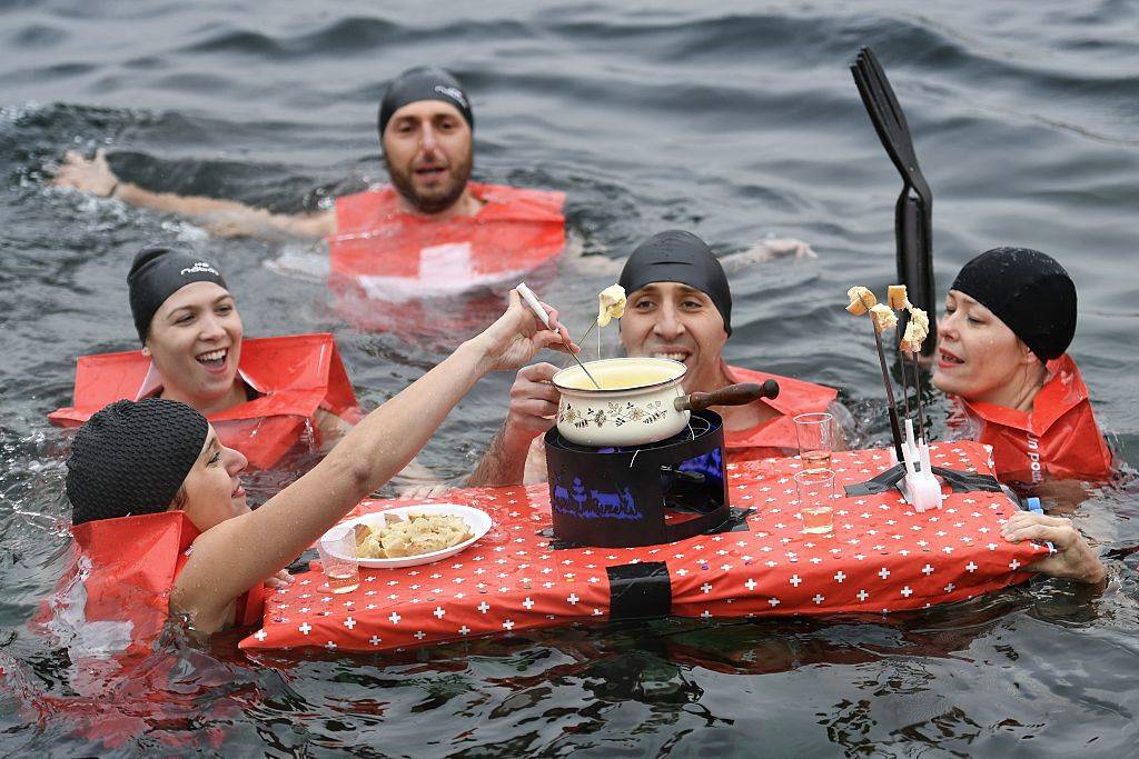 People eat a cheese fondue as they swim