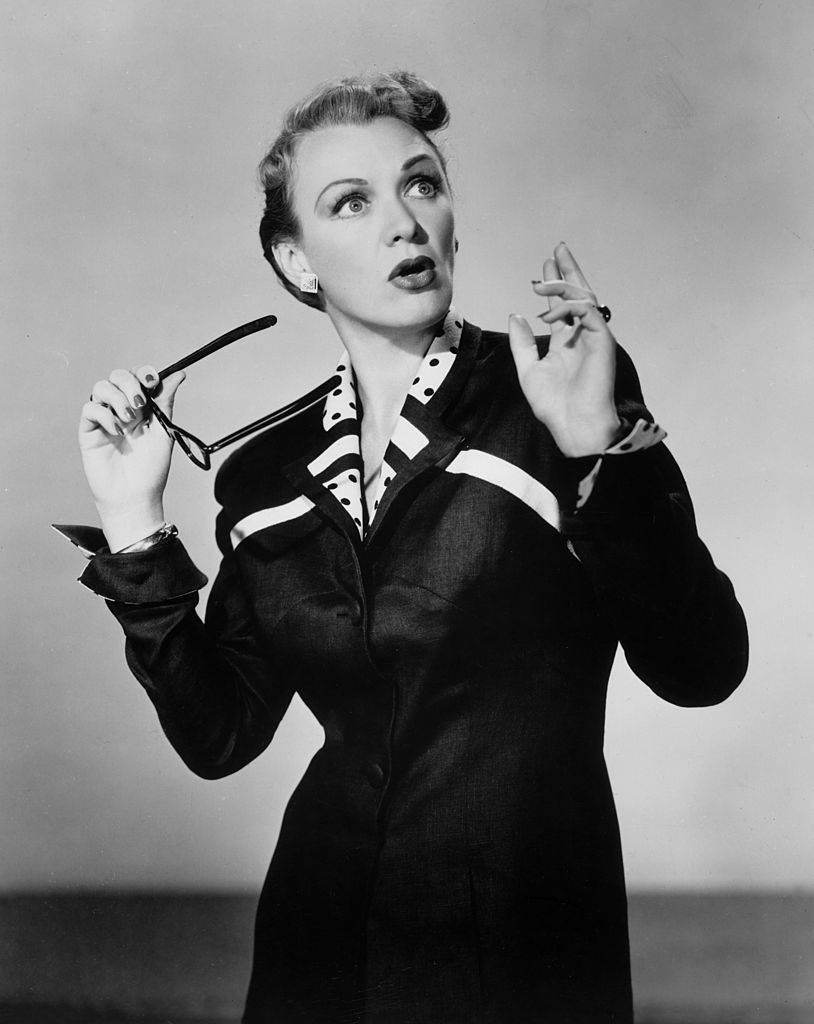 Eve Arden holding a pair of glasses and expressing shock