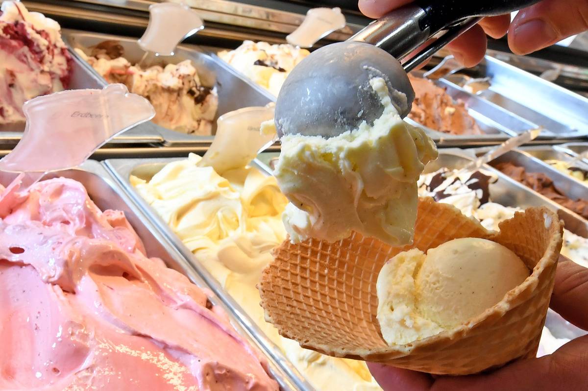 Ice cream parlour close up shot of vanilla ice cream being scooped into waffle dish