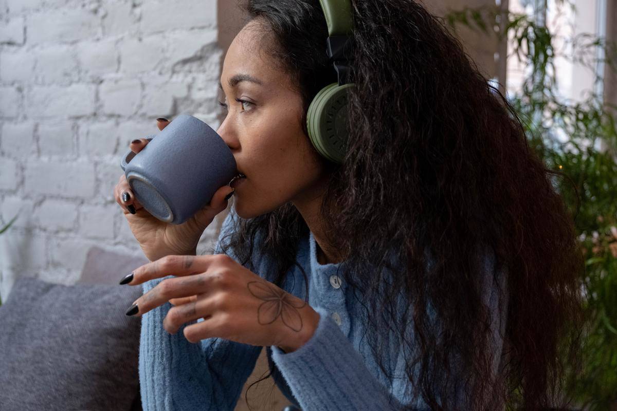 Woman listening to music and drinking from a mug