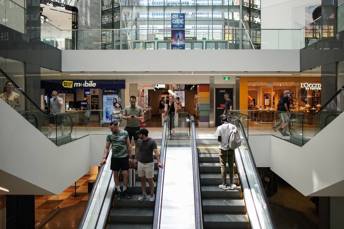 People stand on an escalator in a shopping mall