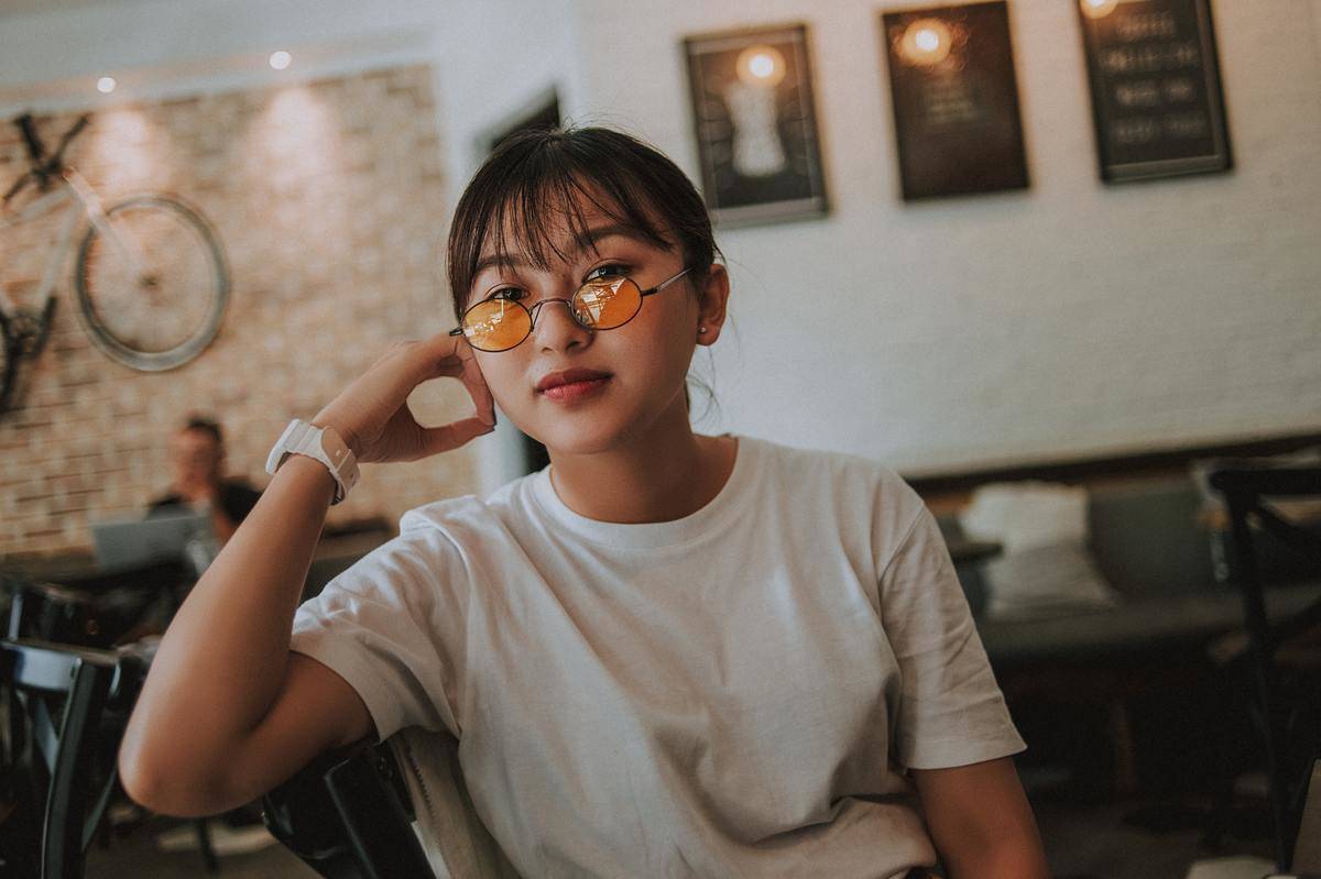 Serious faced young woman wearing orange tinted sun glasses 
