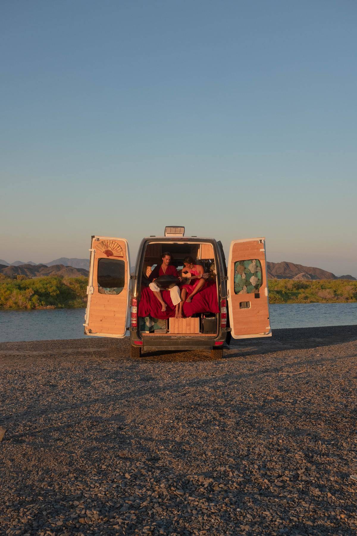 Couple sit in back of travel van 
