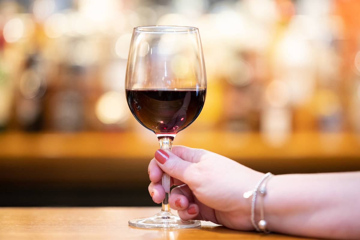 A woman holds a glass of red wine in a pub