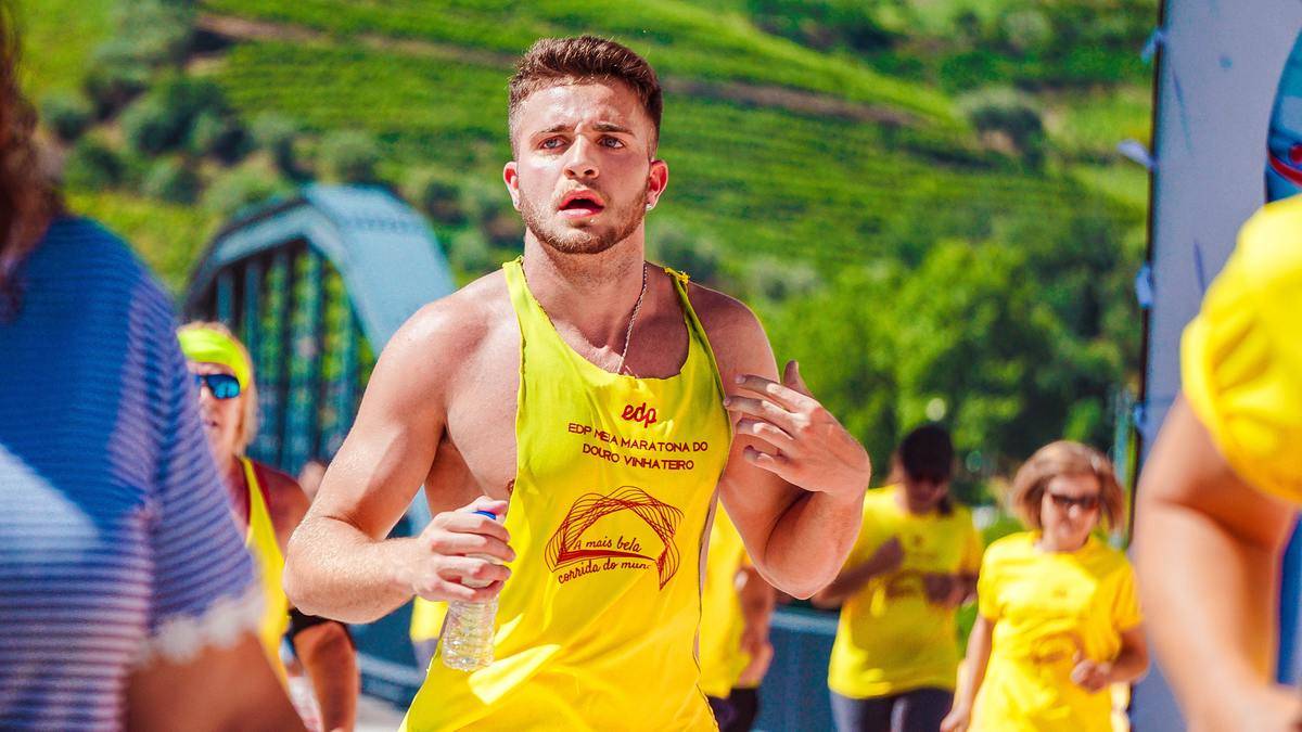 Young man running in marathon wearing bright yellow tank top cut and ripped to expose more chest