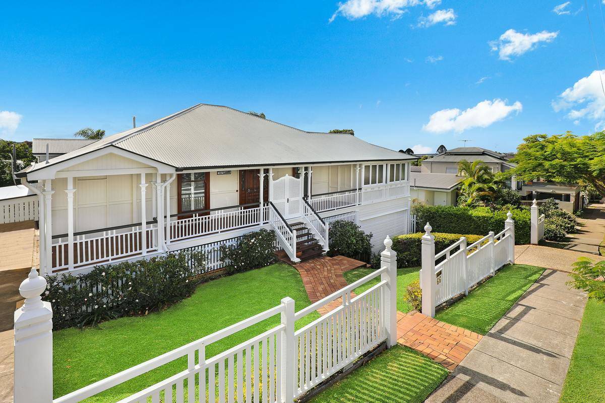 Exterior of a house, with a white fence extending across the front yard