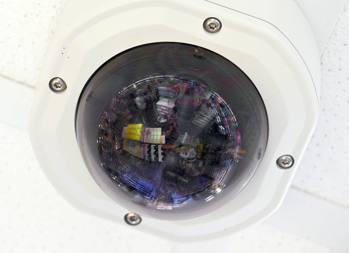 A camera hangs on the ceiling of a store of the retail chain Rewe, goods are reflected in the curve.