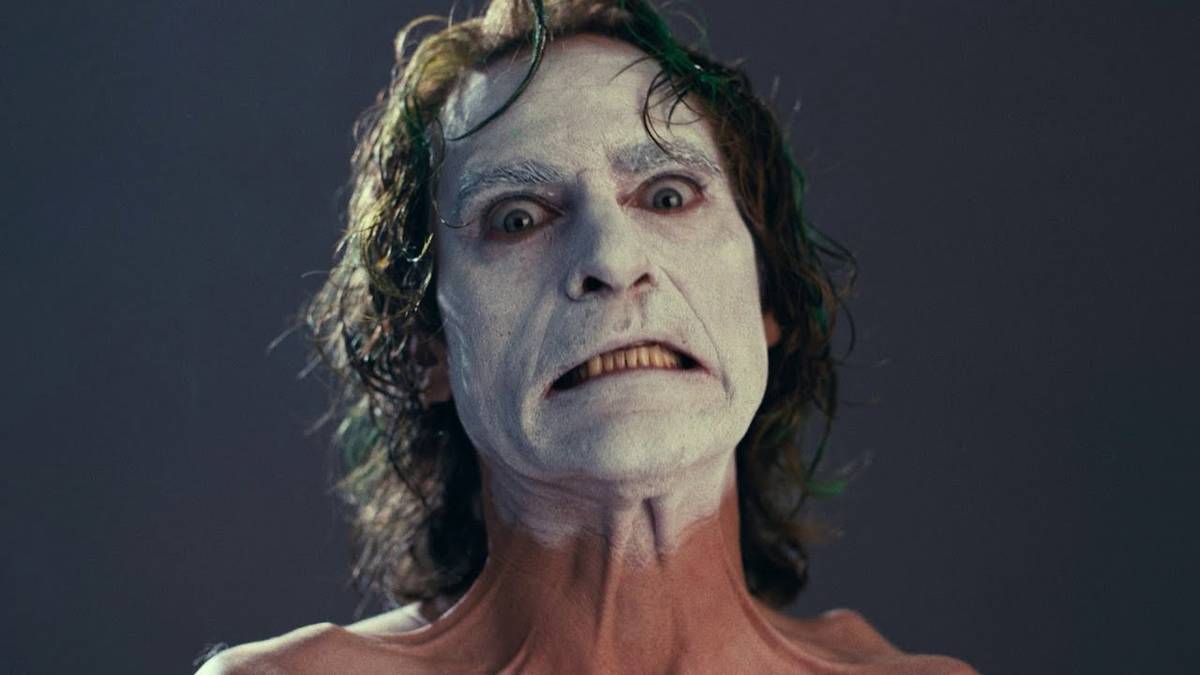 Joaquin Phoenix making a disturbed face with white makeup as Arthur Fleck in Joker