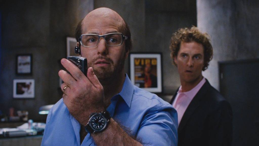Tom Cruise talking into cell phone as Les Grossmann as Matthew McConaughey looks on as Rick Peck in Tropic Thunder