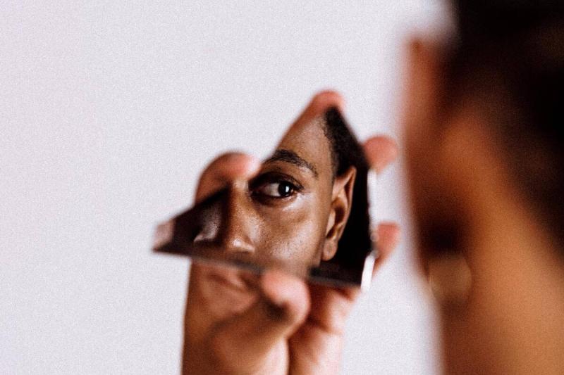 man staring at himself in glass shard
