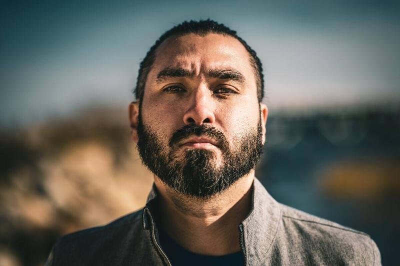 man with beard looking quietly angry in front of natural scene