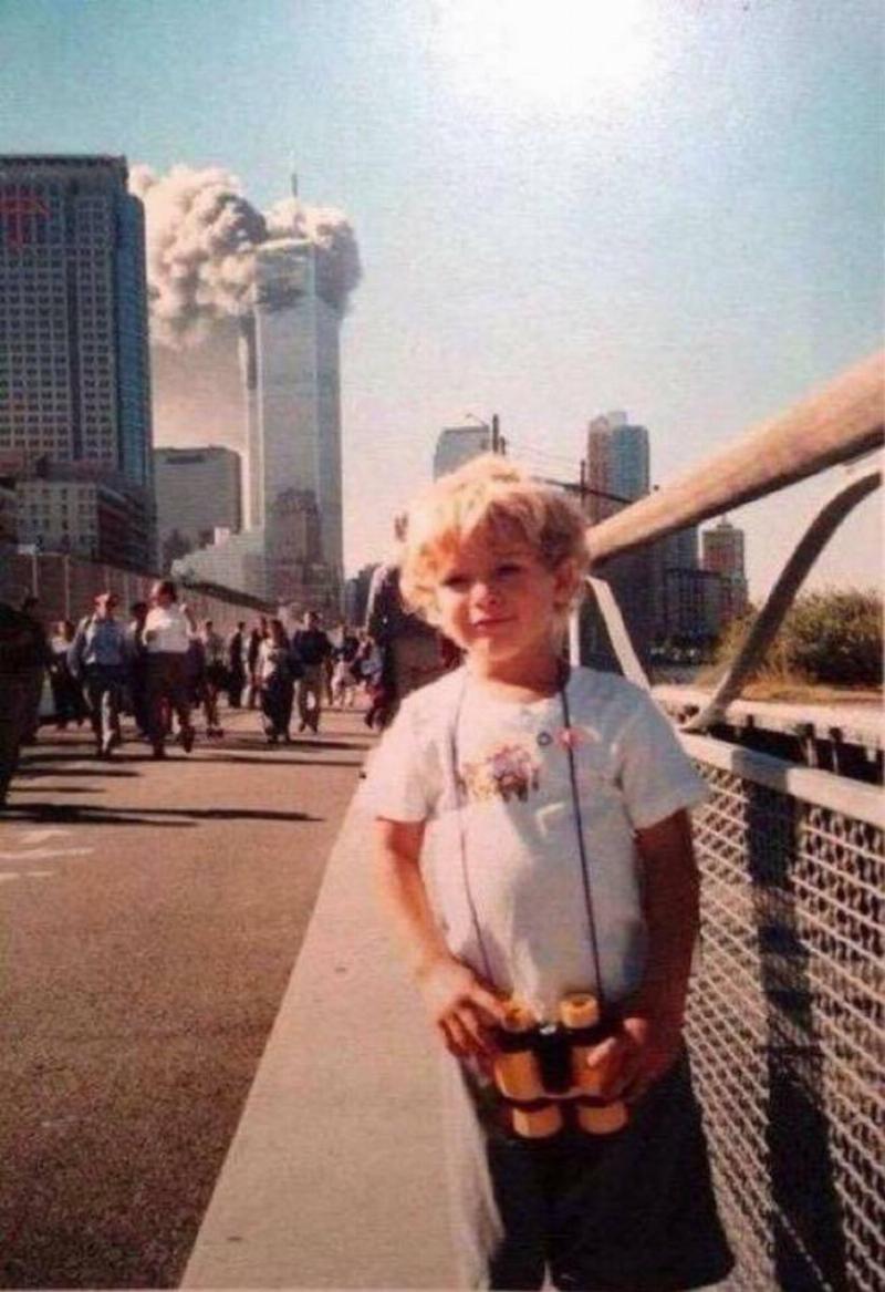 boy standing for photo and in the background there's a plume of smoke on the tower
