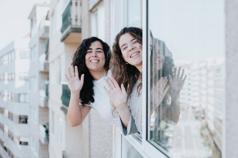 women leaning out of window and waving